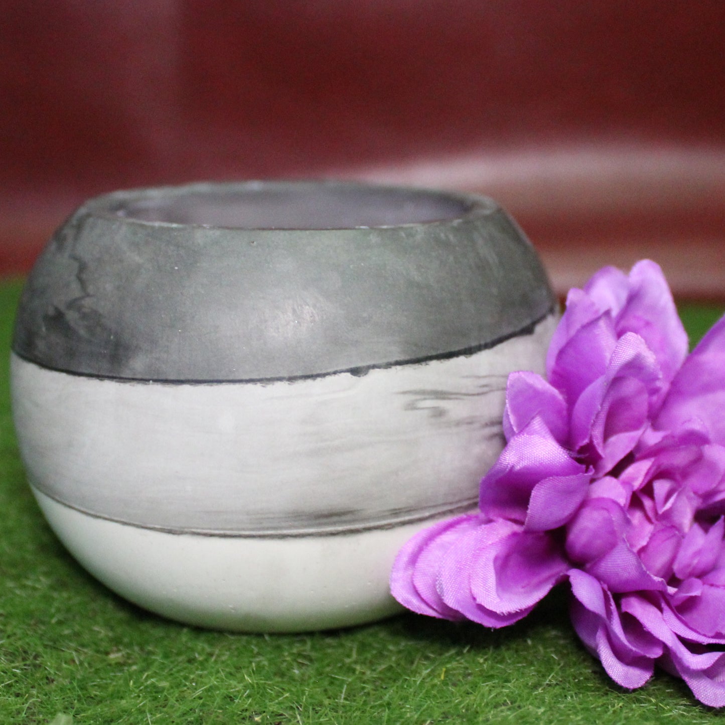 Handcrafted candle holder featuring the black, white and grey hues of the asexual pride flag, seamlessly blended together for a striking design. Set on grass with a burgundy vinyl backdrop, surrounded by a purple flower mirroring the flagās colors, creating a visually rich and identity-affirming scene. Perfect for LGBTQ+ home decor, pride gifts, and statement lighting.
