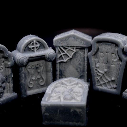 Five tombstone-shaped wax melts set against a black background, with four standing upright encircling a fifth lying flat in the center. A bold, gothic design perfect for dark aesthetic lovers, spooky decor, and macabre ambiance.