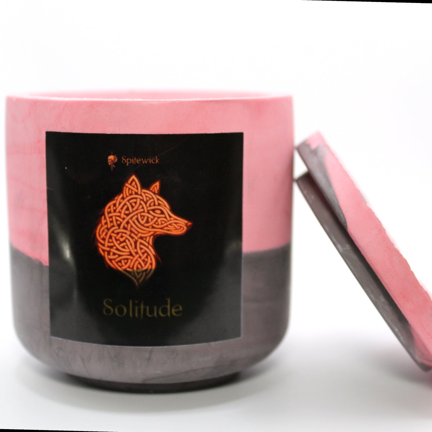 A red and black candle holder with a black label featuring a wolf in elegant gold Celtic knotwork. The name Solitude is displayed in gold beneath the intricate design, adding a bold, mystical touch. The lid is removed and propped against the right side, showcasing the full aesthetic. Set against a clean white background, this handcrafted candle merges tradition and modern artistry, perfect for unique home decor, gifts, and personal expression.