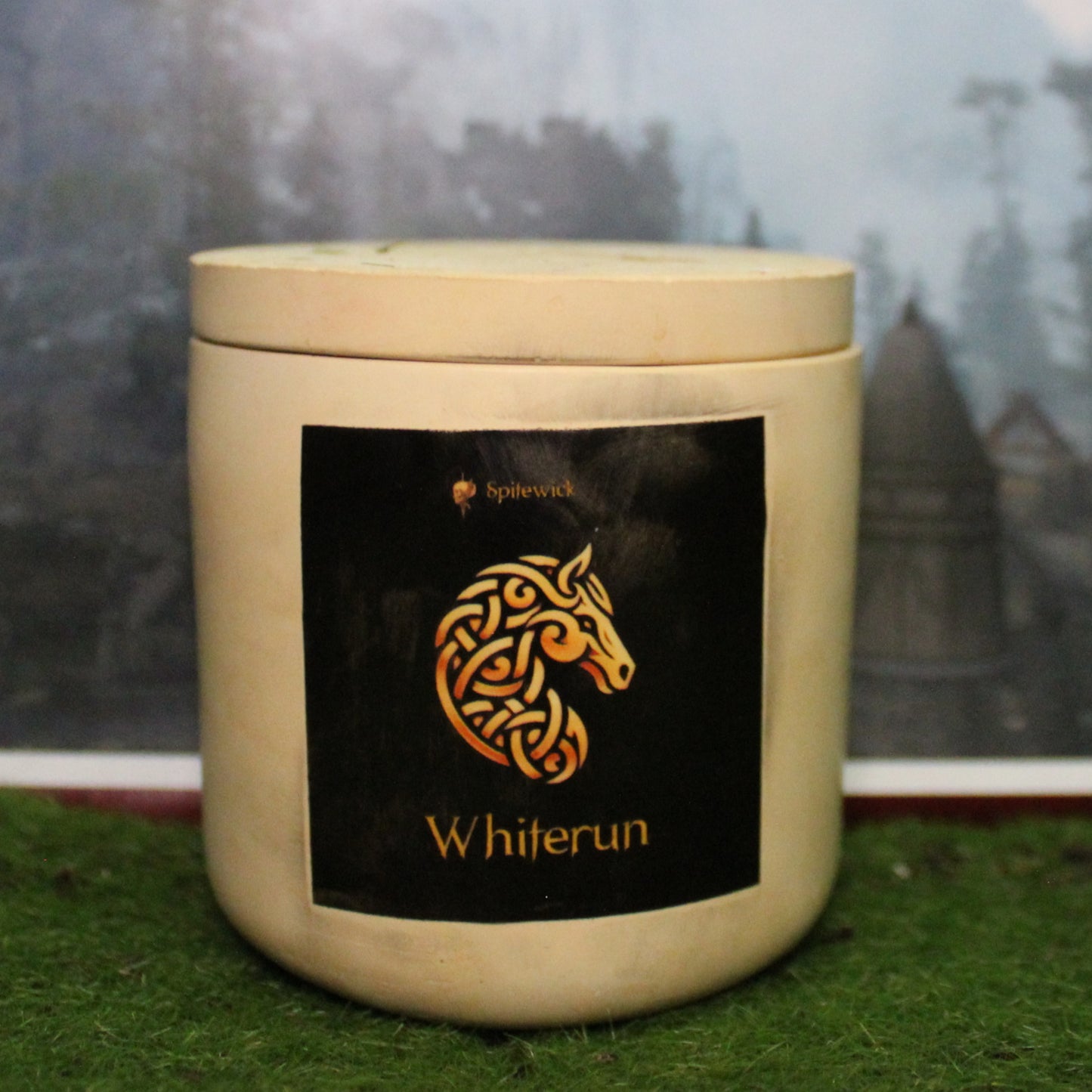 Front view of a handcrafted beige candle holder with a black label featuring an horse in gold Celtic knotwork. The name whiterun is elegantly printed in gold beneath the design. Set on grass, this piece blends artisan craftsmanship with bold identity, making it perfect for unique home decor, gifts, and statement lighting.