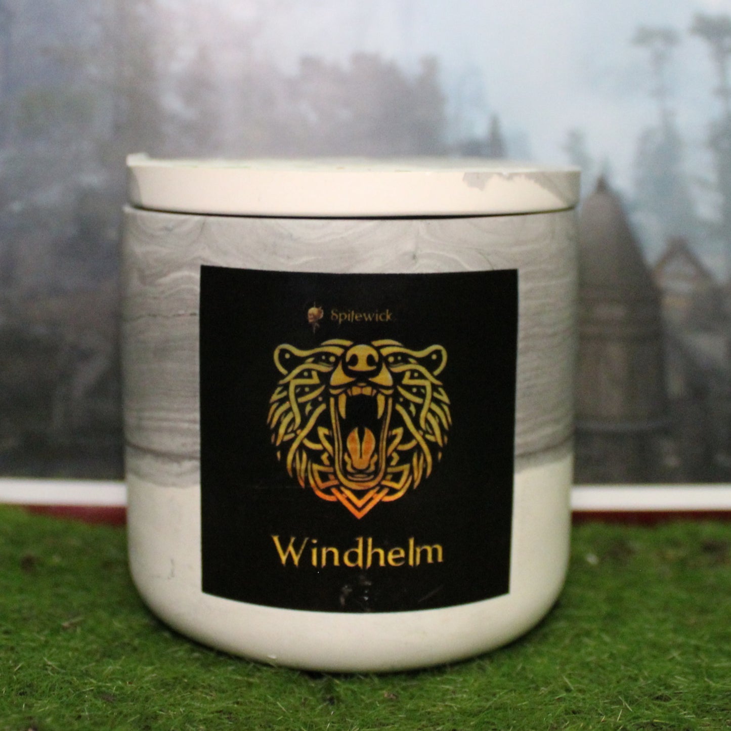 Front view of a handcrafted black and white candle holder with a black label featuring a bear in gold Celtic knotwork. The name Windhelm is elegantly printed in gold beneath the design. Set on grass, this piece blends artisan craftsmanship with bold identity, making it perfect for unique home decor, gifts, and statement lighting.