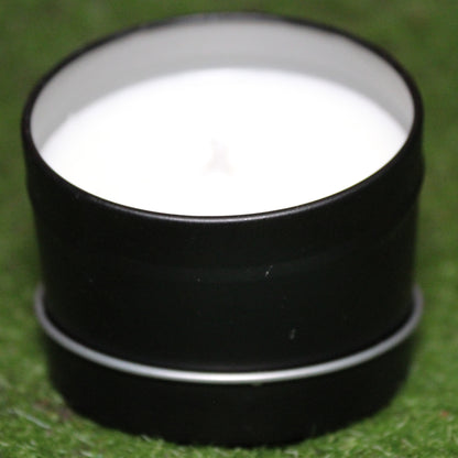 Black metal candle tin holding a white candle, photographed on grass. Handmade Skyrim-inspired candle with soy wax in a reusable container - perfect for unique home decor, gifts, and personal expression.