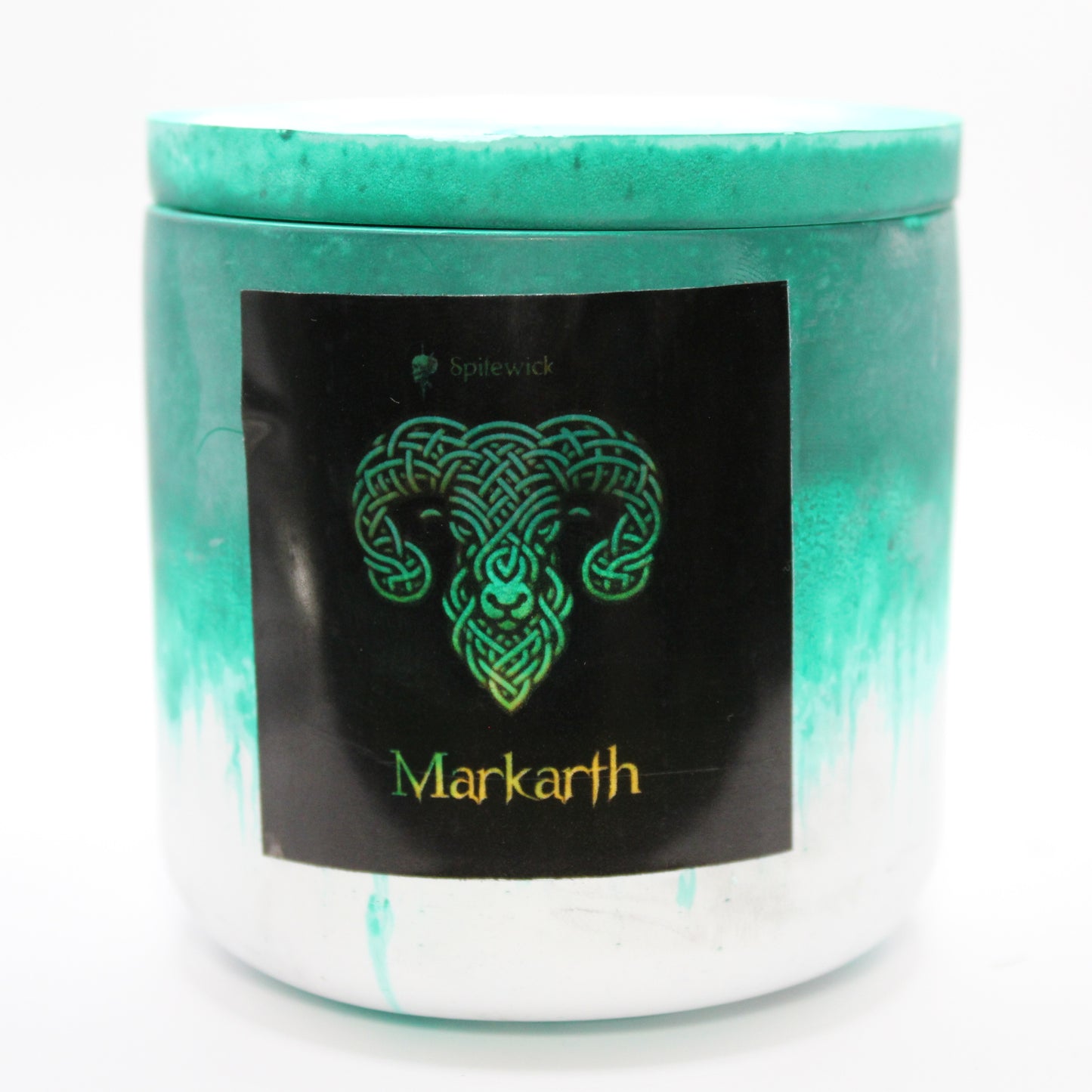 A green and white candle holder with a sleek black label, featuring a ram intricately designed in stylized gold Celtic knotwork. Beneath the design, the name Markarth is elegantly printed in gold, adding a bold yet sophisticated touch. Set against a clean white background, this handcrafted candle blends tradition with modern artistry, perfect for unique home decor, gifts, and personal expression.