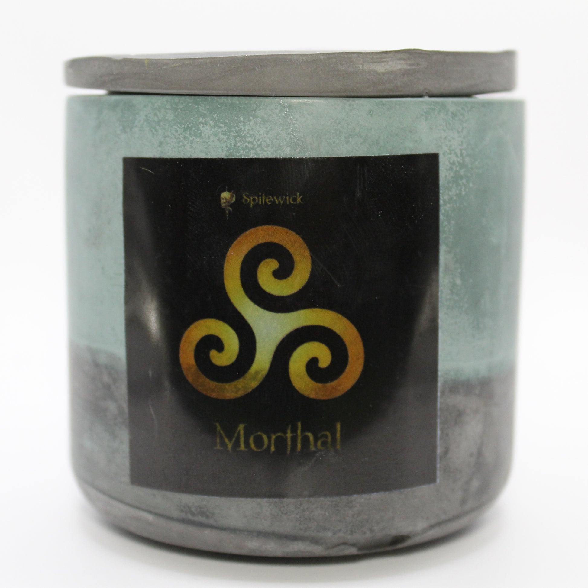 A green and black candle holder with a sleek black label, featuring a Triskele intricately designed in stylized gold. Beneath the design, the name Morthal is elegantly printed in gold, adding a bold yet sophisticated touch. Set against a clean white background, this handcrafted candle blends tradition with modern artistry, perfect for unique home decor, gifts, and personal expression.