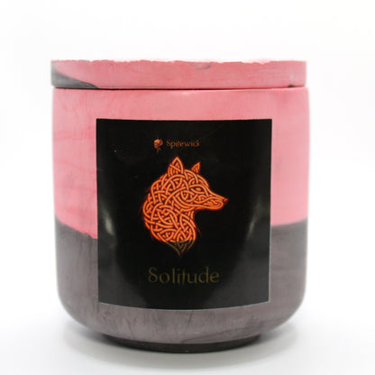 A red and black candle holder with a sleek black label, featuring a wolf intricately designed in stylized gold Celtic knotwork. Beneath the design, the name solitude is elegantly printed in gold, adding a bold yet sophisticated touch. Set against a clean white background, this handcrafted candle blends tradition with modern artistry, perfect for unique home decor, gifts, and personal expression.