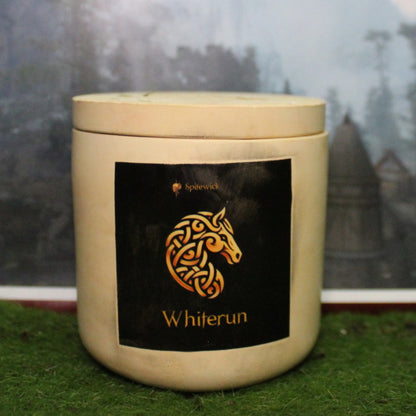 Front view of a handcrafted beige candle holder with a black label featuring an horse in gold Celtic knotwork. The name whiterun is elegantly printed in gold beneath the design. Set on grass, this piece blends artisan craftsmanship with bold identity, making it perfect for unique home decor, gifts, and statement lighting.