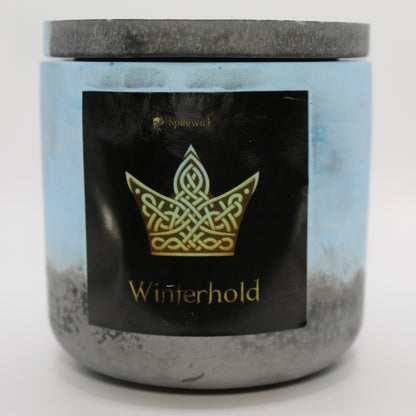 A blue and black candle with a sleek black label, featuring a Crown intricately designed in stylized gold Celtic knotwork. Beneath the design, the name Winterhold is elegantly printed in gold, adding a bold yet sophisticated touch. Set against a clean white background, this handcrafted candle blends tradition with modern artistry, perfect for unique home decor, gifts, and personal expression.