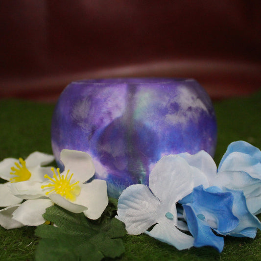 Handcrafted candle holder featuring the Green, white, blue and purple hues of the <Trans-Inclusive Gay Men's pride flag, seamlessly blended together for a striking design. Set on grass with a burgundy vinyl backdrop, surrounded by an assortment of flowers mirroring the flag’s colors, creating a visually rich and identity-affirming scene. Perfect for LGBTQ+ home decor, pride gifts, and statement lighting."